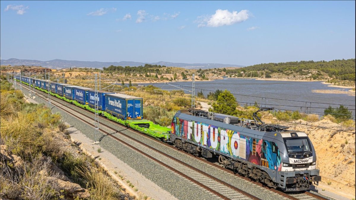 Tren de mercancías con varios semirremolques a bordo en una autopista ferroviaria.