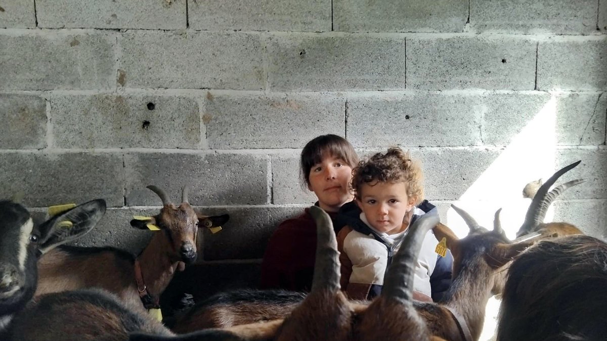 María, que cambia de vida y se muda al campo a sus 30 años, posa con su hijo y algunas de sus cabras