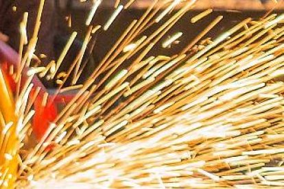 Un trabajador de la industria metalúrgica sierra una pieza de chapa. PQS / CCO
