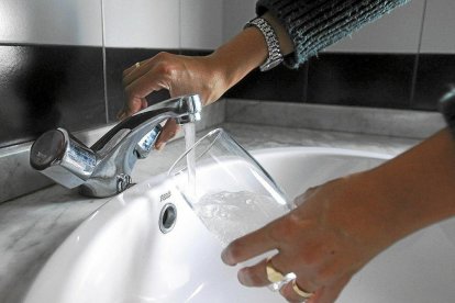 Una mujer echa agua del grifo en un vaso de cristal, en una imagen de archivo.- E.M