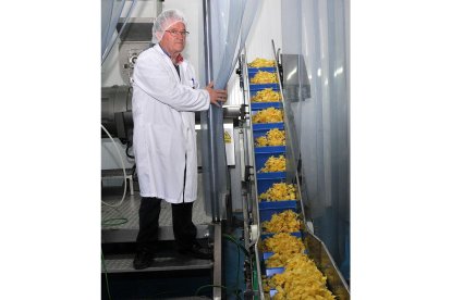 Carlos Garijo junto a una línea de patatas recién fritas.  / VALENTÍN GUISANDE