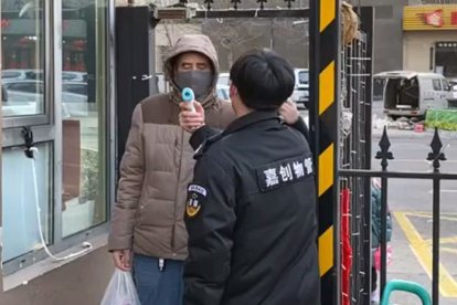 El guardia de la comunidad de vecinos donde reside la soriana tomando la temperatura. CRISTINA GARCÍA