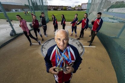 Julio Calvo posa en la jaula con su colección de medallas, arropado por sus alumnos, que posan con discos y martillos. - J.M. LOSTAU