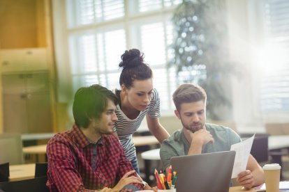 Group of business executives discussing over laptop at their desk in the office