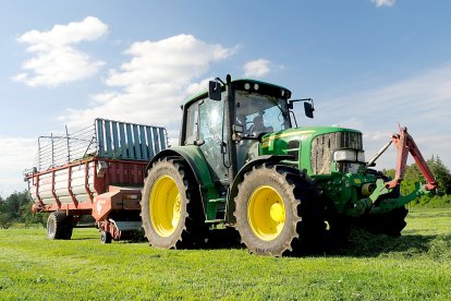 Un agricultor conduce un tractor con su maquinaria de arrastre en una explotación agrícola.