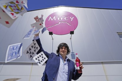 Arturo González, frente a Bodegas Mucy, con una baraja y uno de sus vinos claretes