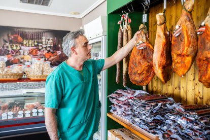 Santiago Alonso observa uno de los jamones con su característico pimentonado, tradicional de la zona y que da a las piezas un aspecto característico.