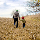 Un padre y su hijo recorren a pie un campo de cultivo. PQS / CCO