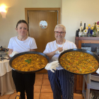 Eva Munera y Laura Fernández con dos paellas antes de servir a la mesa en el restaurante Villa Mencía en Corullón.  /