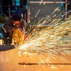 Un trabajador de la industria metalúrgica sierra una pieza de chapa. PQS / CCO