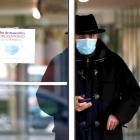 Un usuario sale de un centro de salud de Valladolid con la mascarilla puesta, junto a un cartel que recuerda su uso obligatorio. PHOTOGENIC