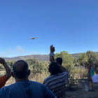 Los vecinos observan uno de los aviones que trabaja en la extinción del incendio de Navalacruz.- ICAL