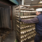 PANADERIA MANRIQUE. Un trabajador introduce en el horno un carro con barras de pan en una fábrica de Valladolid. Horizontal