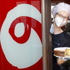 Carol se asoma a la puerta de su tienda obrador con uno de sus bizcochos.- SANTI OTERO