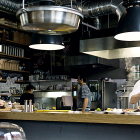 Un chef, dos ayudantes y una camarera atienden la cocina de un restaurante .-PQS/CCO