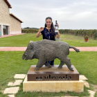 Lucía San José, frente a la escultura realizada por Ricardo Flecha, con una botella de su vino Madremía.