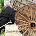 UNA MUJER ANCIANA DESCANSA SENTADA JUNTO A UN CARRO Y SU MULETA