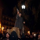 Participantes del Entierro de Genarín en León durante una procesión nocturna, con un hombre alzando una botella bajo una farola