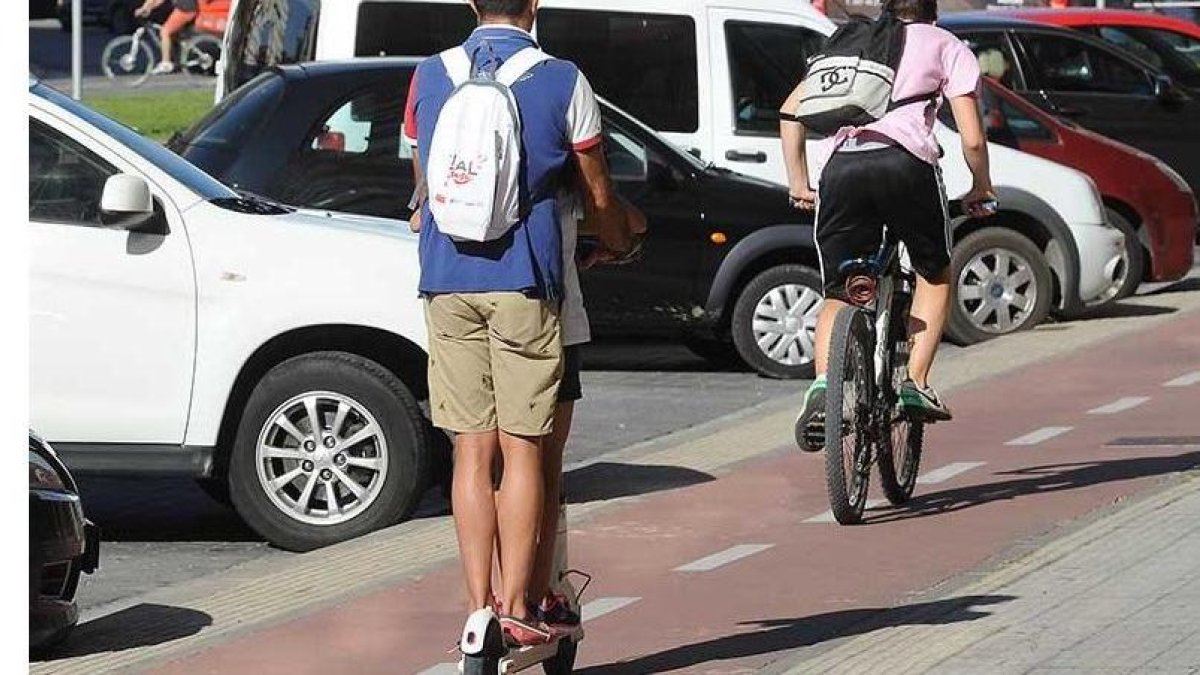 Un hombre circula en patinete y otro en bicicleta