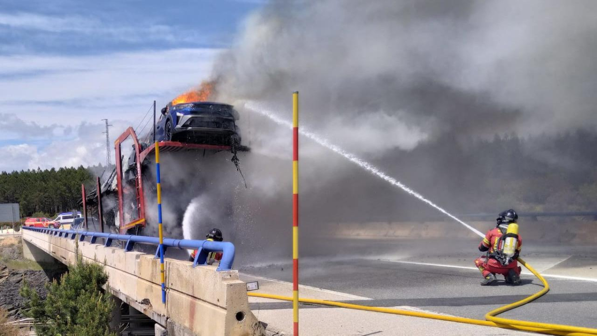 Operarios de los bomberos apagan las llamas de los vehículos incendiados.