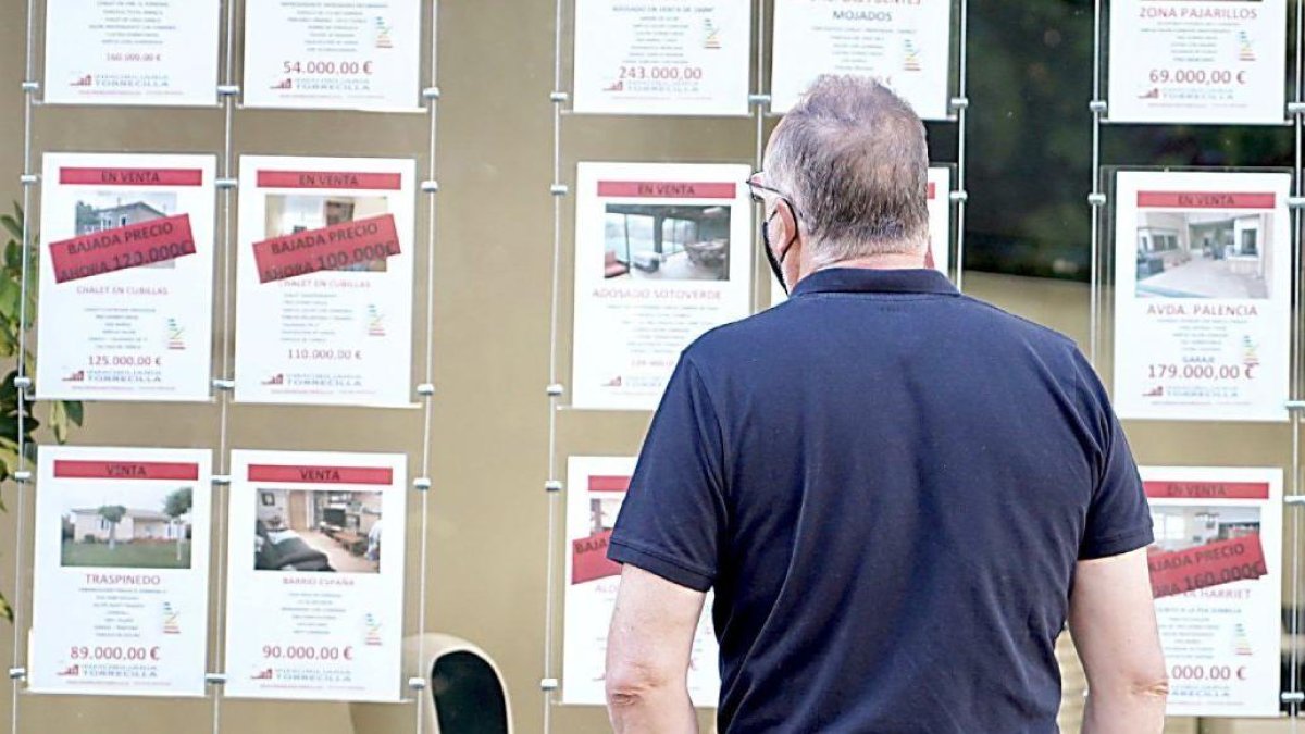 Un vecino observa las ofertas de pisos en venta y alquiler en una inmobiliaria de Valladolid. ICAL