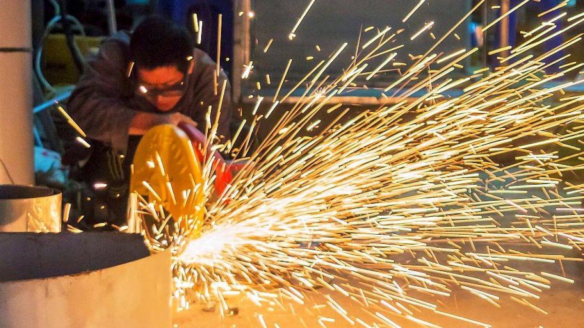 Un trabajador de la industria metalúrgica sierra una pieza de chapa. PQS / CCO