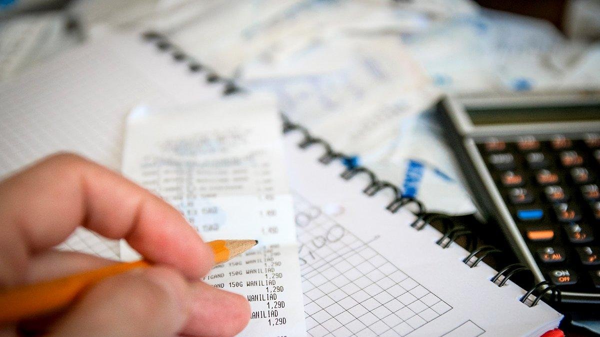 Un ciudadano calcula los gastos de su hogar con calculadora y lápiz.