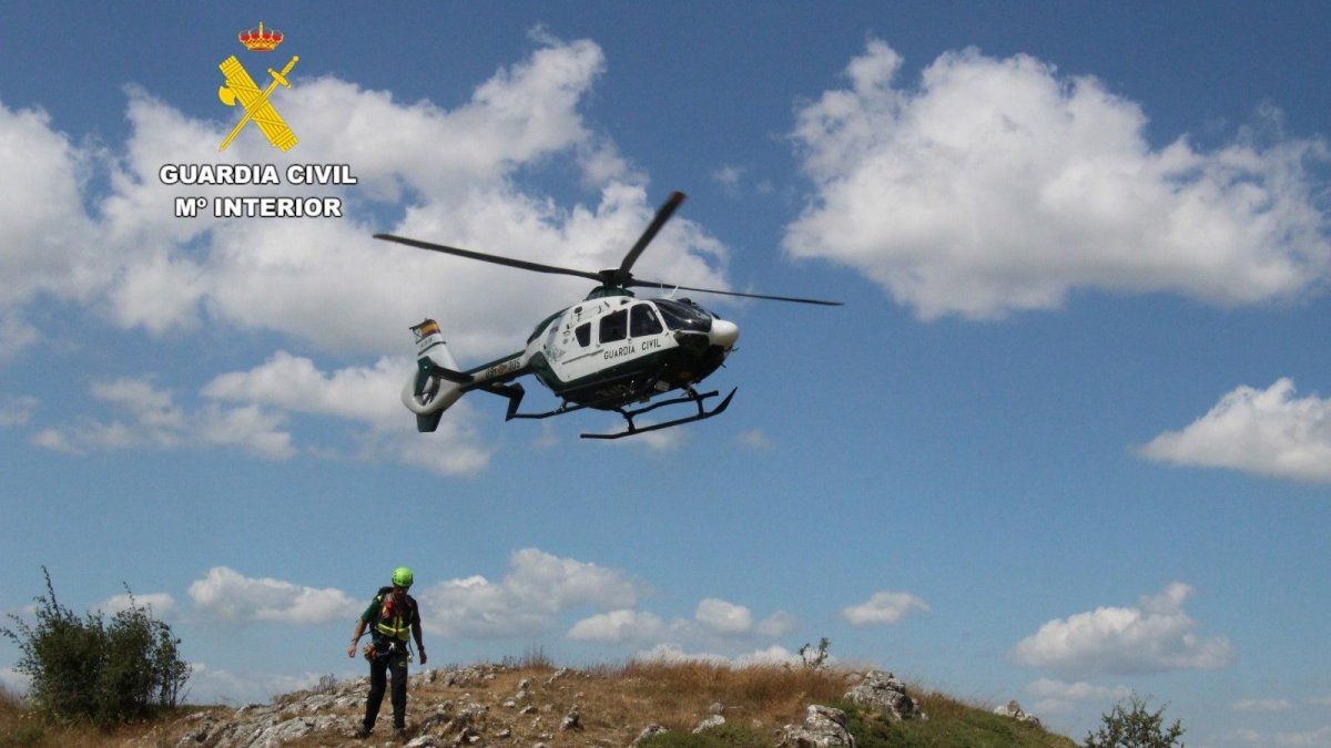 Imagen del helicóptero y uno de los agentes del Greim que rescataron a los senderistas en la Ruta Mielgo (León).