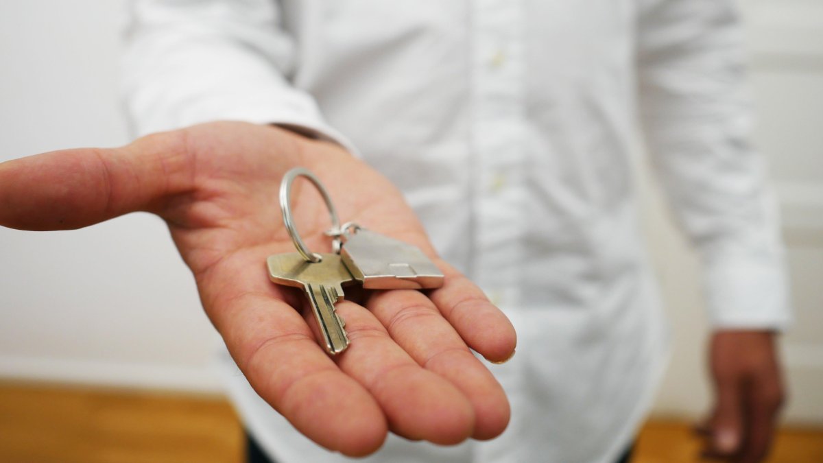 Un arrendador ofrece la llave de su apartamento.