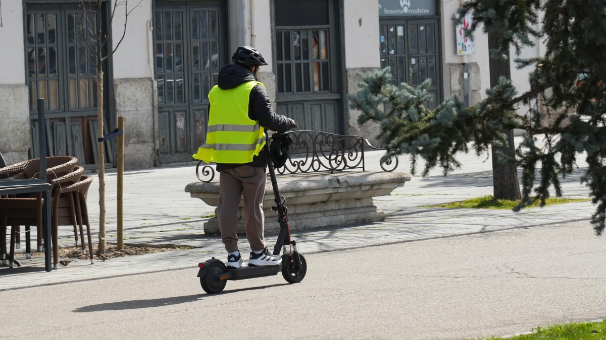 Un conductor de patinete eléctrico por la acera de Recoletos de Valladolid.