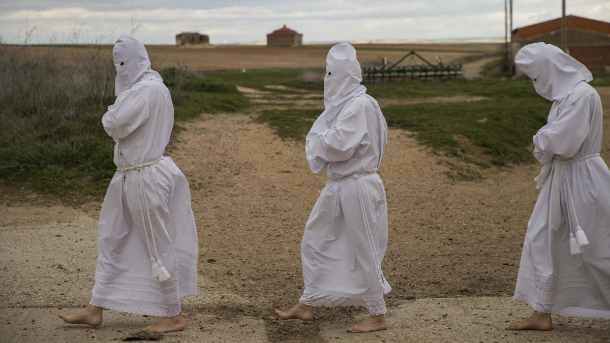 Unos penitentes en la Procesión de La Carrera en Villarrín de Campos (Zamora), al fondo unos palomares.