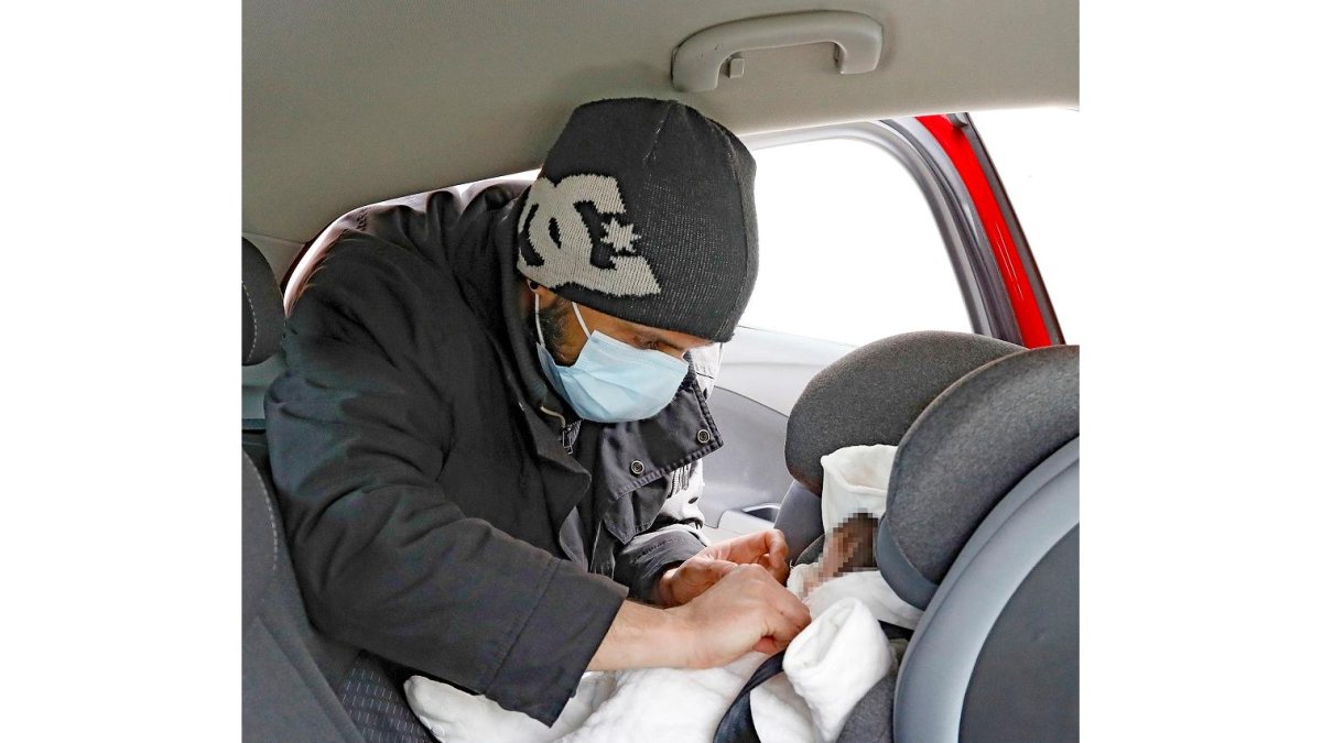 Un padre abrocha a su bebé al grupo cero del coche antes de viajar. -J.M. LOSTAU