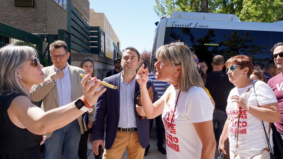 Los representantes de los trabajadores de Siro hablan por teléfono con Mañueco mientras el autobús del Gobierno les espera.- ICAL