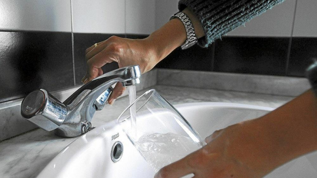 Una mujer echa agua del grifo en un vaso de cristal, en una imagen de archivo.- E.M