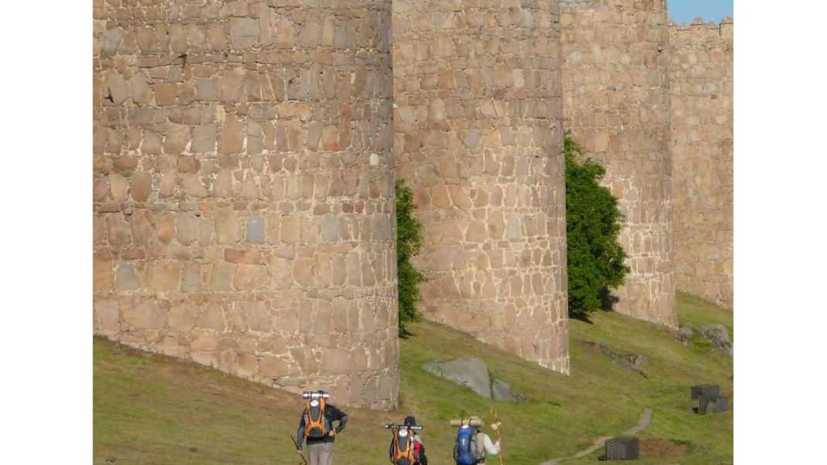 Peregrinos transitan por el camino que discurre paralelo a la Muralla de Ávila.- ÁVILA TURISMO