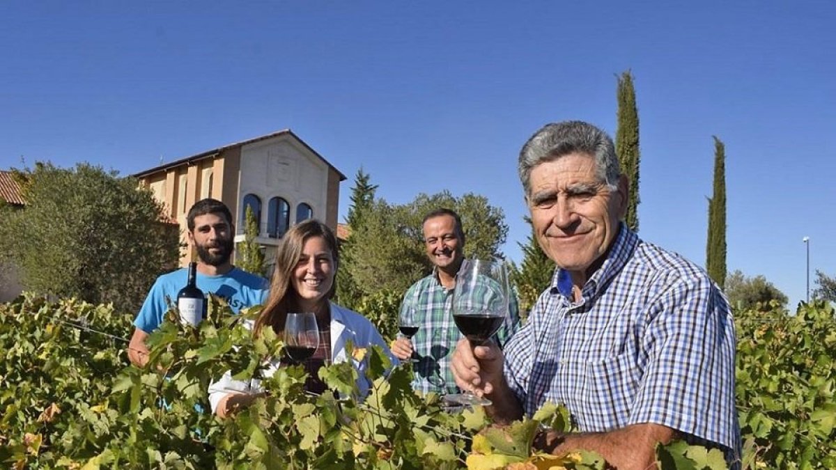 Moisés Gamazo en primer plano, seguido de Esther Pérez, Jesús Herranz y Víctor en el viñedo que está delante de la fachada de la bodega.