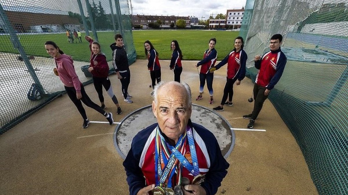 Julio Calvo posa en la jaula con su colección de medallas, arropado por sus alumnos, que posan con discos y martillos. - J.M. LOSTAU