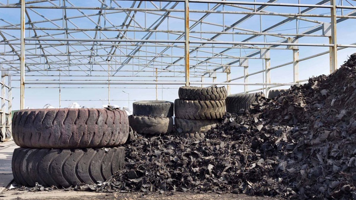 Close up of old used tires and shredded tire pile in background