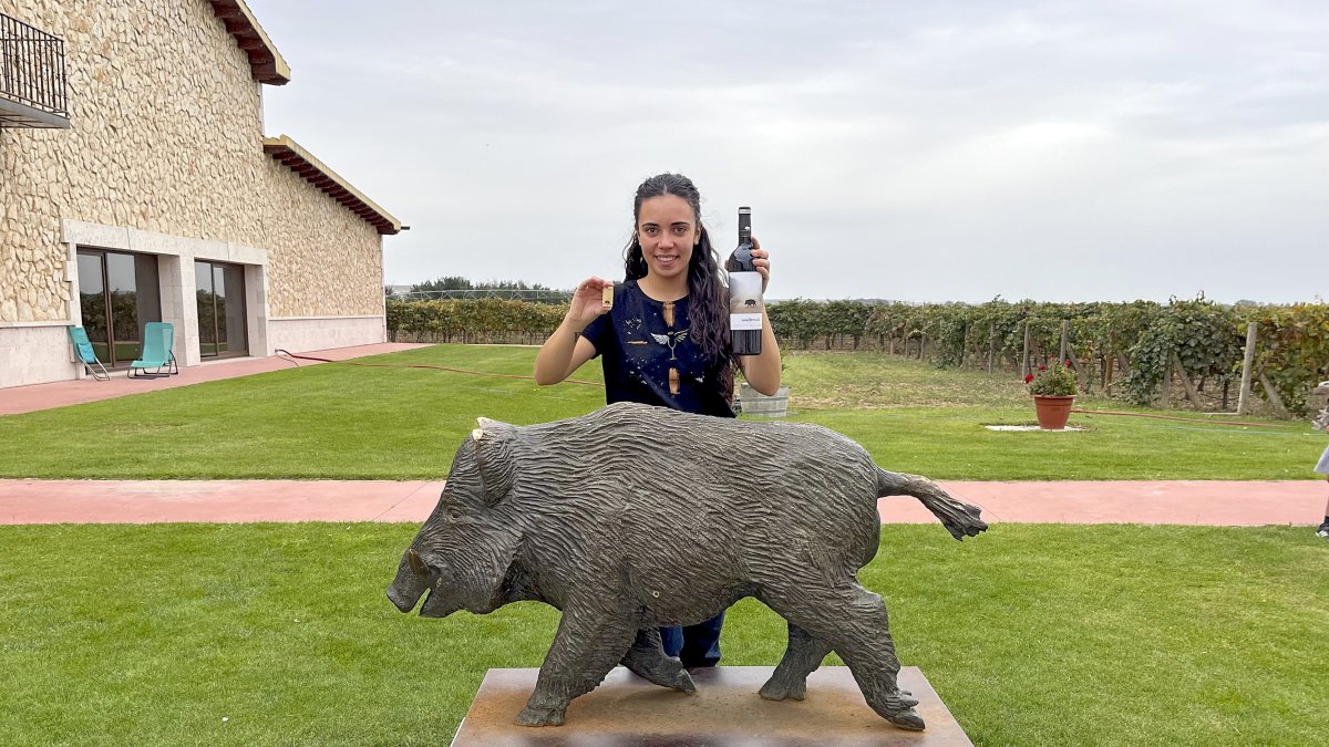 Lucía San José, frente a la escultura realizada por Ricardo Flecha, con una botella de su vino Madremía.