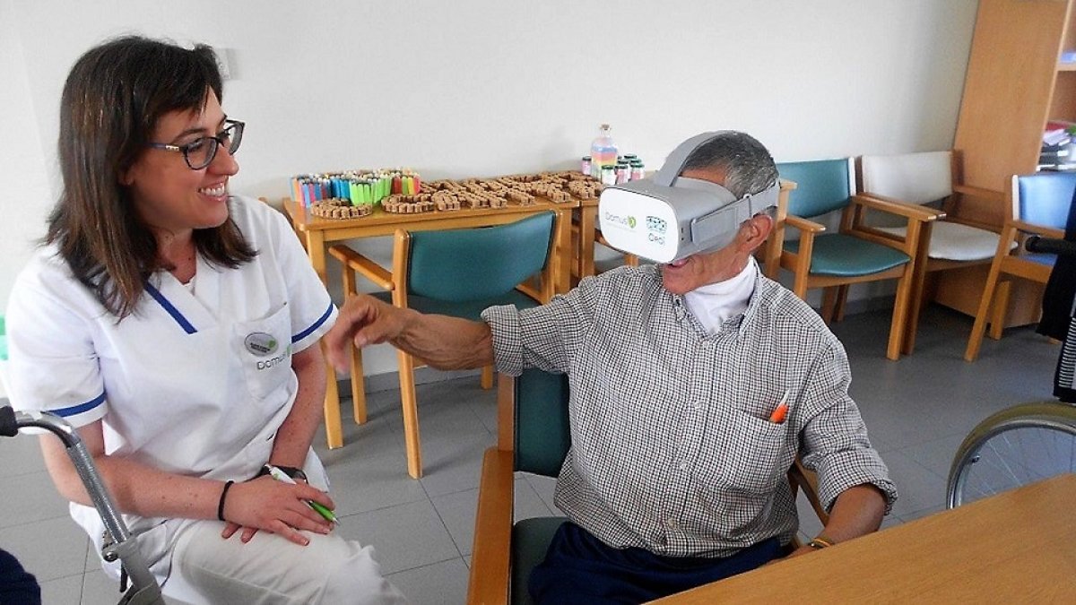 Un anciano prueba el vídeo musical inmersivo junto con personal de la residencia. | EL MUNDO