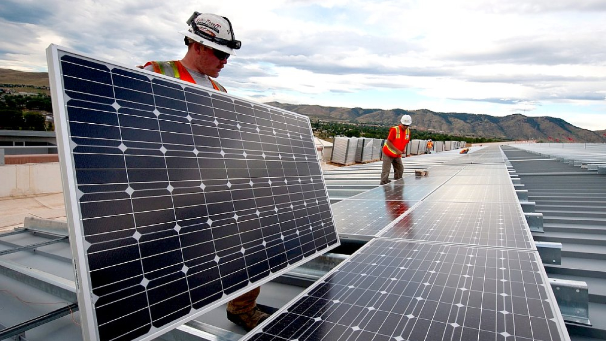 Dos operarios instalan paneles solares en el tejado de una edificación. PQS / CCO