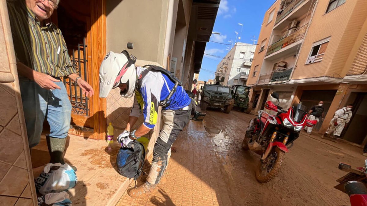 Un motero entrega productos básicos a un afectado por la DANA en Valencia