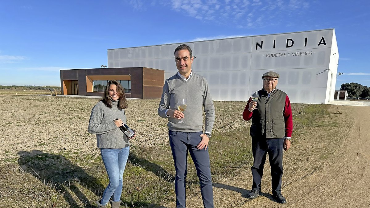 En primer plano, Daniel Torio; a su espalda, la enóloga Silvia; y delante de la fachada de la nueva bodega, su padre Ángel Torio