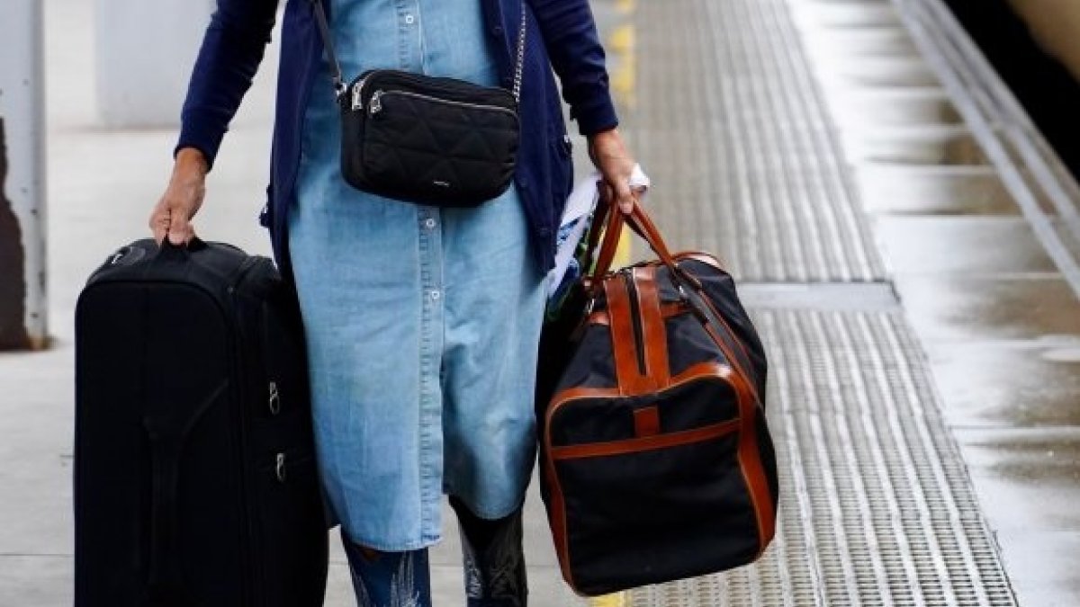 Una persona carga con maletas en una estación de ferrocarril.