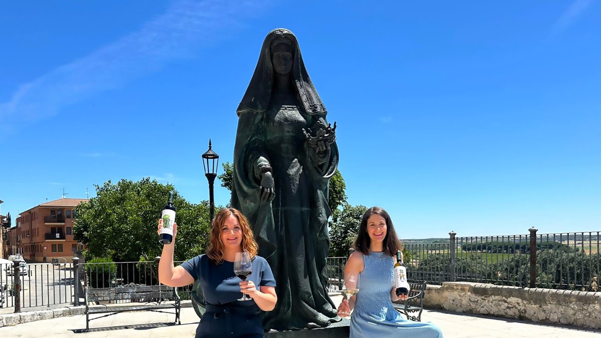 Helena Muelas y su hermana Reyes sentadas a los pies de la escultura de la Reina Juana, frente a las casas del Tratado en Tordesillas.
