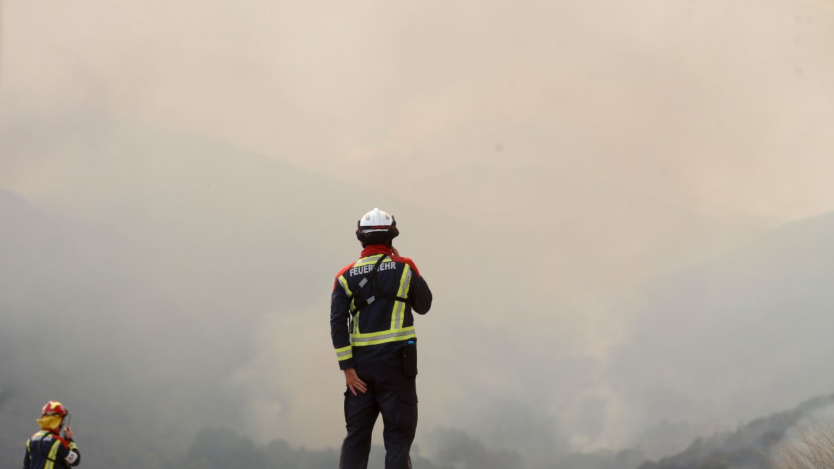Varios bomberos observan el incendio forestal en La Baña, León