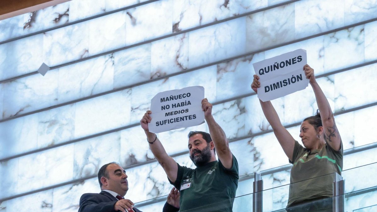 Brigadistas forestales muestran pancartas durante la comparecencia de Mañueco en las Cortes.