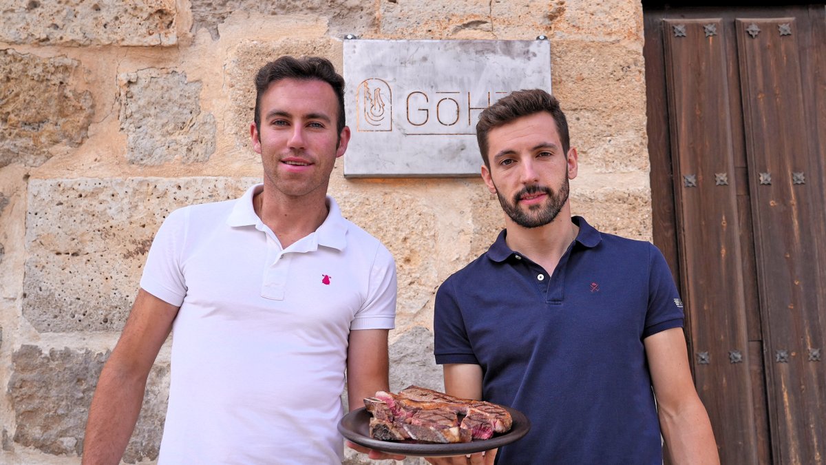 Carlos del Amo y Borja Martín a la puerta del restaurante con un plato de carne roja