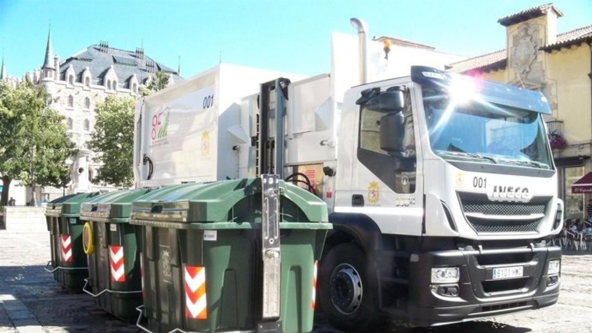 Un camión de basura al lado de unos contenedores en León.