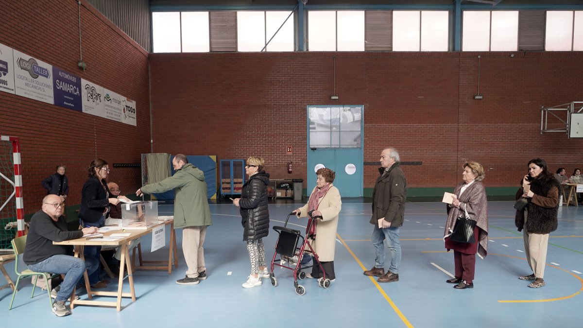 Varios votantes hacen cola para depositar su papeleta.